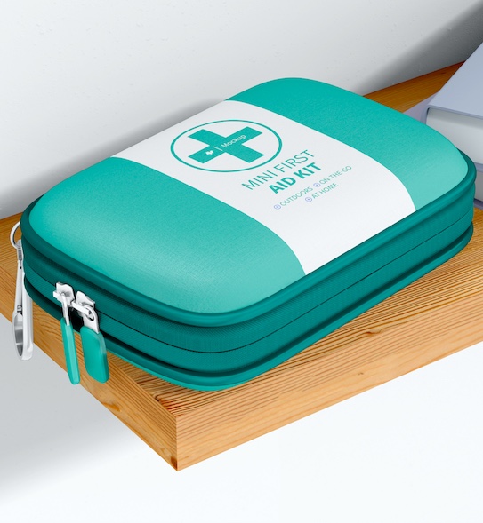 A turquoise mini first aid kit with a white label and cross sits on a wooden surface.